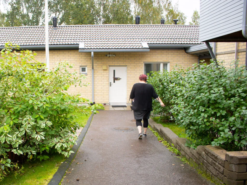 Henkilö kävelee kohti Myrrin keltatiilistä matalaa rakennusta.