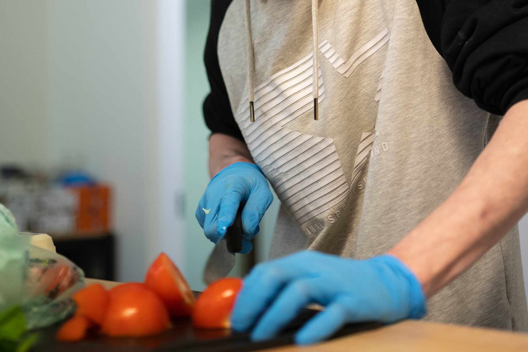 Henkilö leikkaa tomaatteja siivuiksi.